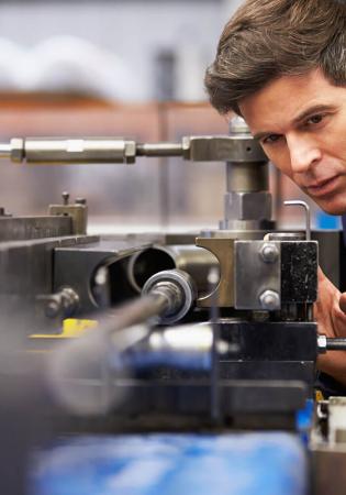 Technician setting up machine tool in advance of running parts for a custom hydraulic system.