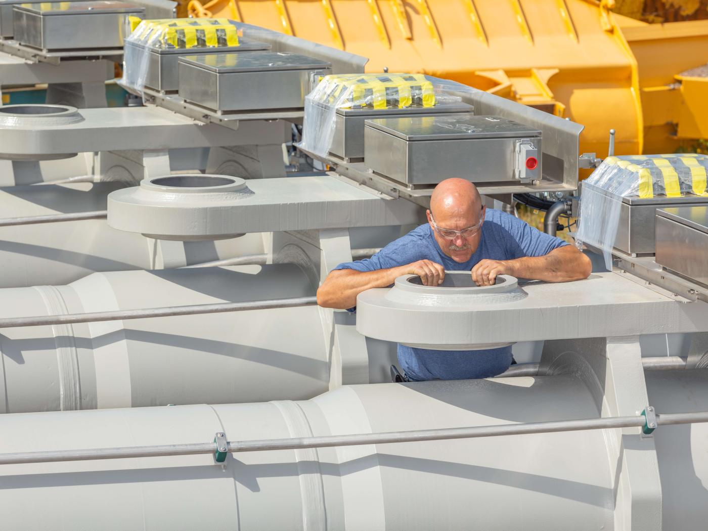 Large, long-stroke custom hydraulic cylinders for hydroelectric dam outlet gate being inspected by engineer .