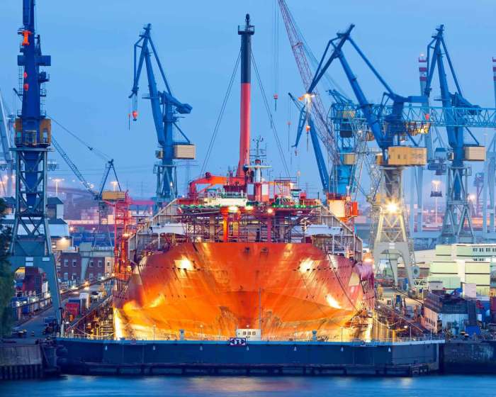 Ship in drydock for repairs at night with cranes in background