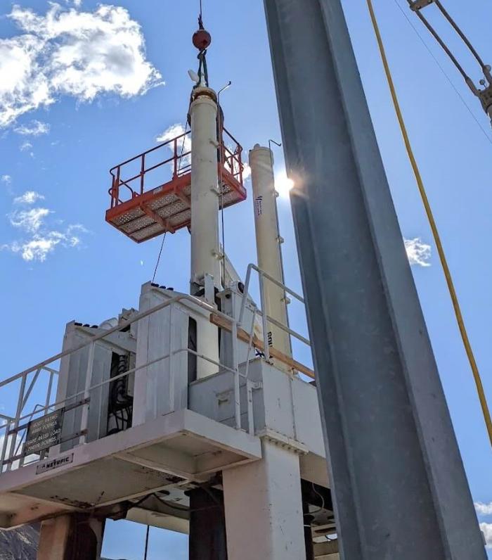 Large hydraulic cylinders being installed at hydroelectric dam on sunny day