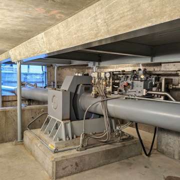 Custom large bore cylinder with gimbal and onboard valve assembly for a lock miter gate installed in a machinery room