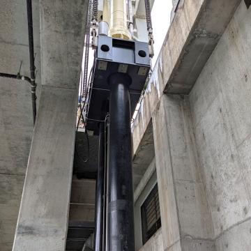Long stroke hydroelectric dam gate cylinders on support beam being lowered into position upon installation